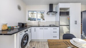 A compact kitchen with a washing machine, a sink, a stove, and a refrigerator.
