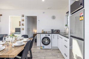 A compact kitchen with a washing machine, a refrigerator, and a dining area with a table set for four.