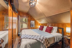 A cozy room with a bed, a bedside table, a lamp, and a window with curtains. - Bearfoot Cabin - Central Tahoe Cabin (South Lake Tahoe)