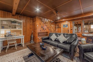 A wooden interior with a sofa, a coffee table, a dining table, and a staircase. - Bearfoot Cabin - Central Tahoe Cabin (South Lake Tahoe)