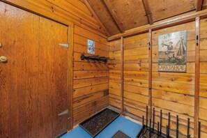 A wooden cabin interior with a door, a poster of Lake Tahoe, and a metal rack with hooks. - Bearfoot Cabin - Central Tahoe Cabin (South Lake Tahoe)