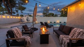 An outdoor patio area with seating, a pool, and string lights.