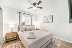 A bedroom with a bed, bedside tables, a ceiling fan, a window with curtains, and a wall-mounted artwork. - Modern 3 bd Oasis, Pool, Spa, Fire Pit, Vegas Strip, Allegiant Stadium (Las Vegas)