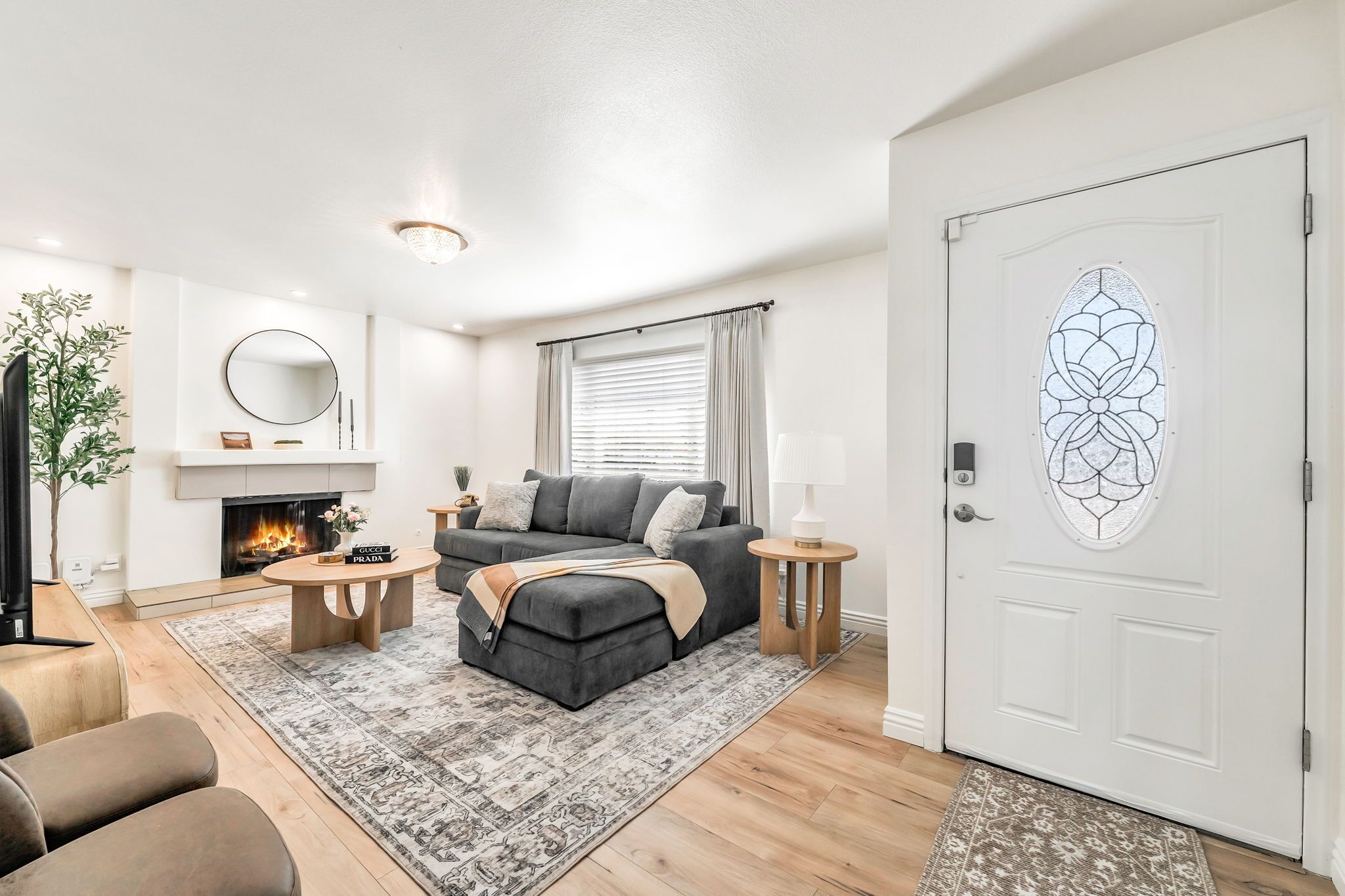 A modern living room with a fireplace, a grey sofa, a coffee table, and a patterned rug.