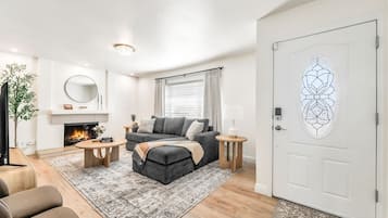 Una sala de estar moderna con chimenea, un sofá gris, una mesa de centro y un tapiz estampado.
