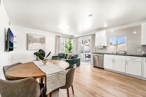 A modern kitchen with white cabinets, a stainless steel dishwasher, and a window with a view.