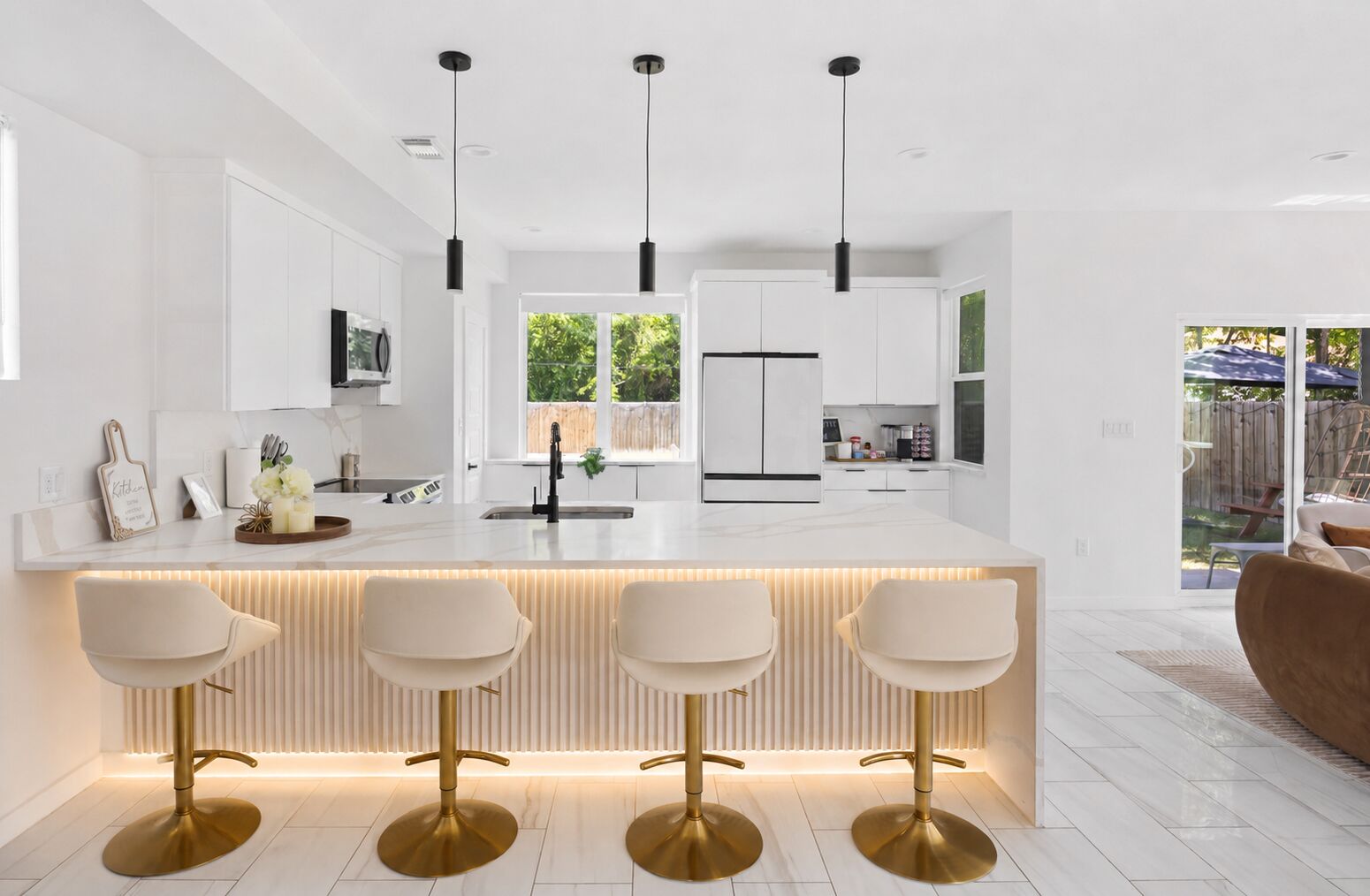 A modern kitchen with a central island, pendant lighting, and a view to the outdoors.