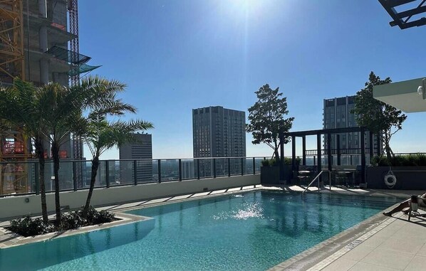 Ein Pool auf dem Dach mit freiem Blick auf umliegende Hochhäuser.