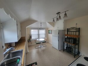 Cocina equipada con refrigerador, microondas y lavaplatos. Zona de comedor con mesa y sillas.