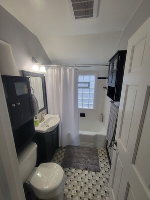 Un baño con inodoro, lavamanos, bañera y ventana.