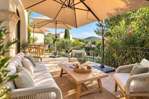 A sunlit outdoor seating area with a pool view, furnished with sofas and a table. - Villa Vany - Provence & View (Éguilles)