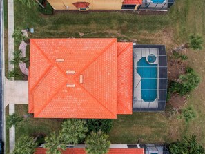 A residential area with a swimming pool, a red-roofed house, and surrounding greenery. - Palms & Pixie Dust Villa - Pool (Davenport)
