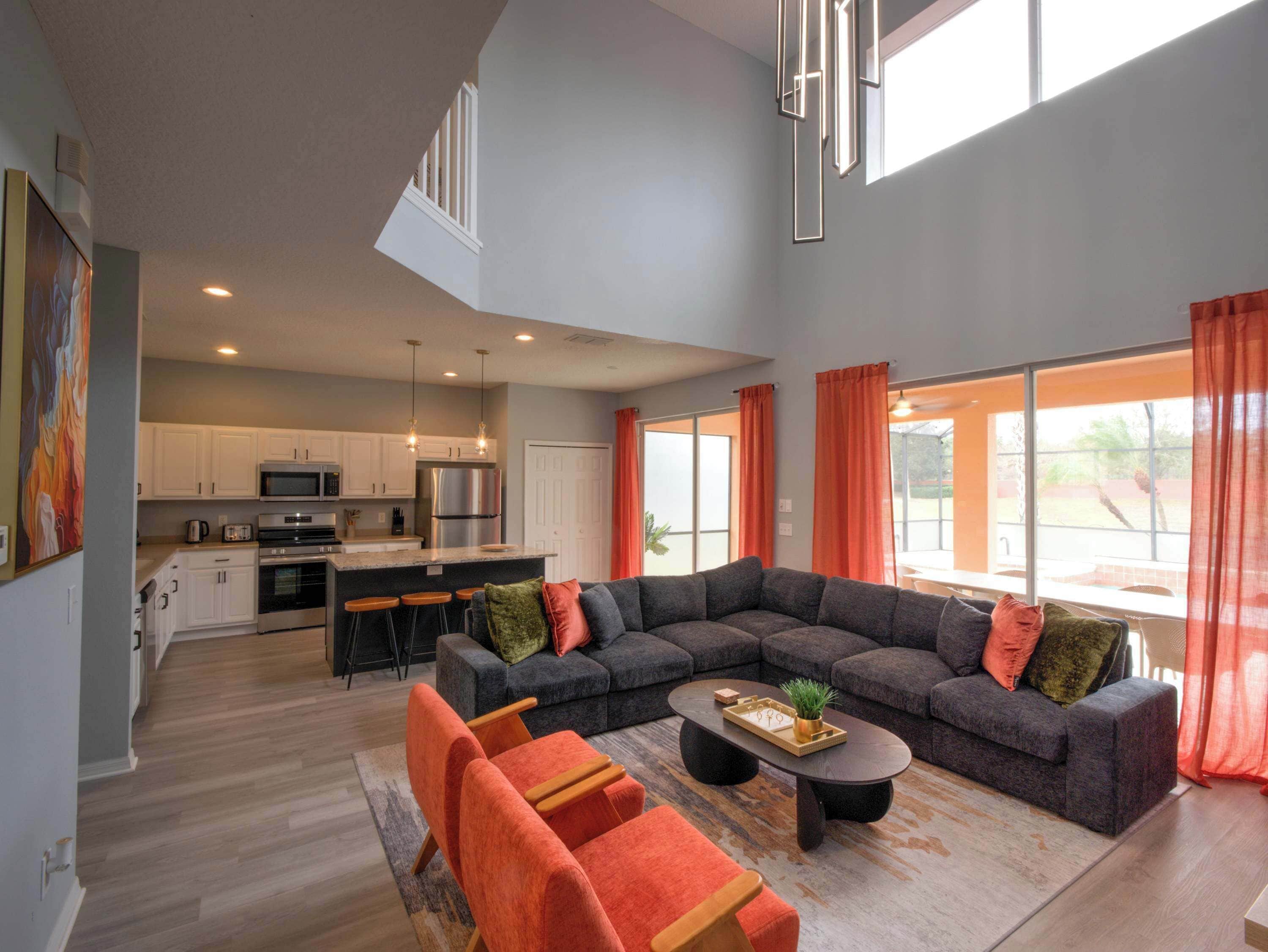 A modern living room with a sectional sofa, a coffee table, and a kitchen in the background.