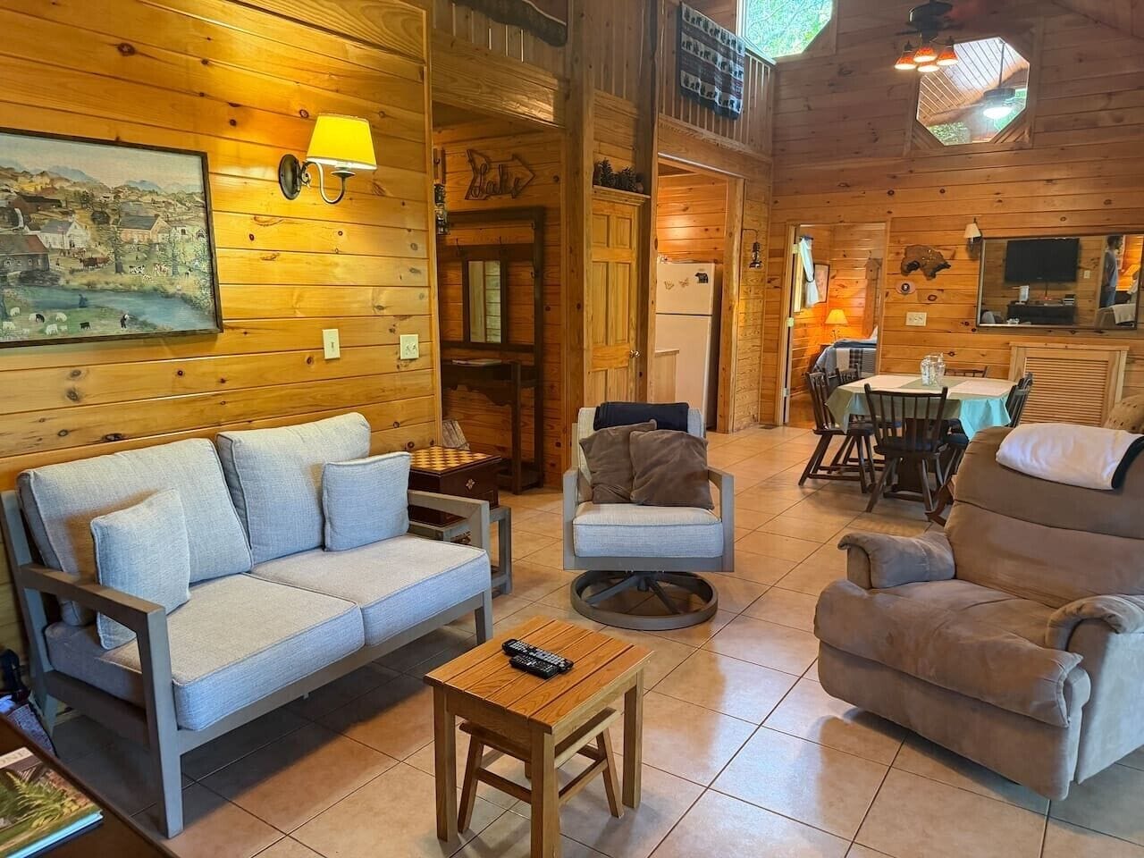 Un interior acogedor con sofá, sillón y una mesita con un control remoto.
