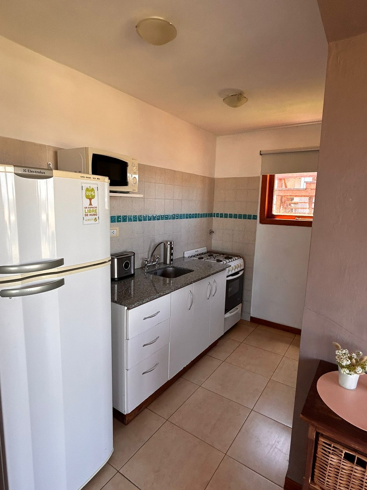 Una cocina compacta con refrigerador, estufa, lavamanos y armarios.