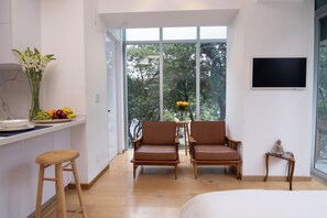 A modern room with a large window, two brown chairs, a small table, and a bed. - Mini Loft w/ Cibeles Fountain View - Balcony & AC (Ciudad de México)