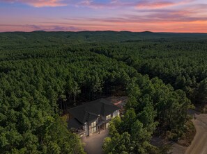 Ein Haus, umgeben von dichtem Wald, mit blauem Himmel.