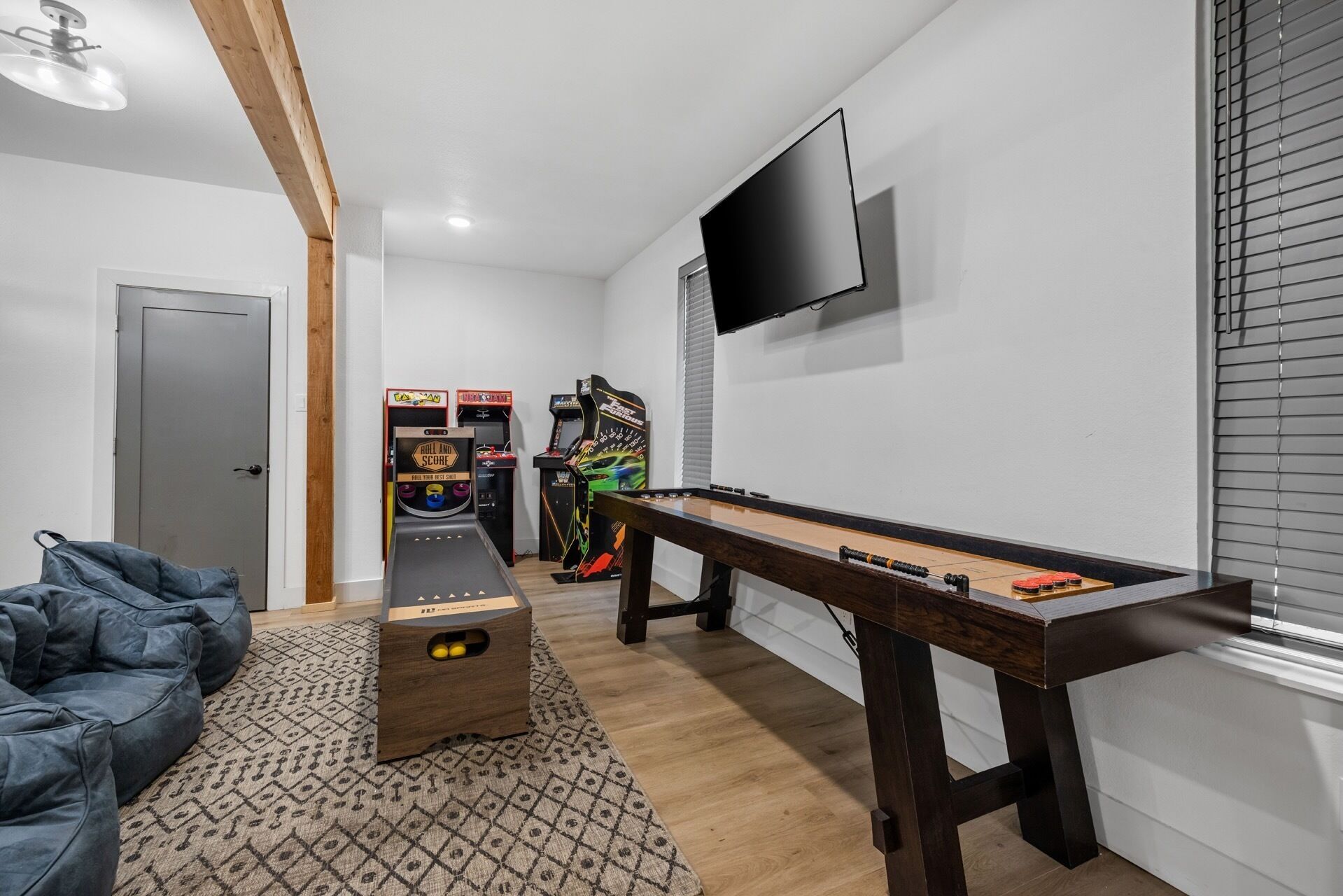 Ein Raum mit einer Fußballstoßmaschine, Spielautomaten, einem an der Wand befestigten Fernseher und einer Tür.