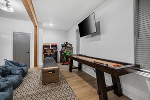 Ein Raum mit einer Fußballstoßmaschine, Spielautomaten, einem an der Wand befestigten Fernseher und einer Tür.