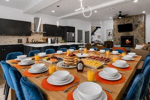 Een moderne keuken met donkere kastjes, een betegelde achterwand en een eethoek met blauwe stoelen en oranje placemats.