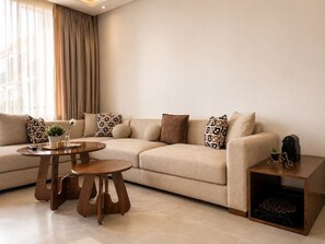 Un salon moderne avec un canapé beige, des coussins à motifs, une table basse en bois et une petite table d’appoint agrémentée d’une plante.