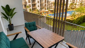 Ein Balkon mit Holztisch und grünen Sitzkissen.
