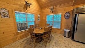 A wooden interior with a round dining table, chairs, and a refrigerator. - Buffalo Valley Retreat-Secluded 2-bedroom cabin 8 minutes from Jasper (Jasper)