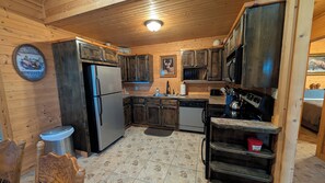 A kitchen with wooden cabinets, a refrigerator, a stove, and a sink. - Buffalo Valley Retreat-Secluded 2-bedroom cabin 8 minutes from Jasper (Jasper)