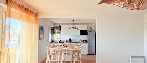 A modern living room with a sofa, a dining table, and a kitchen in the background.