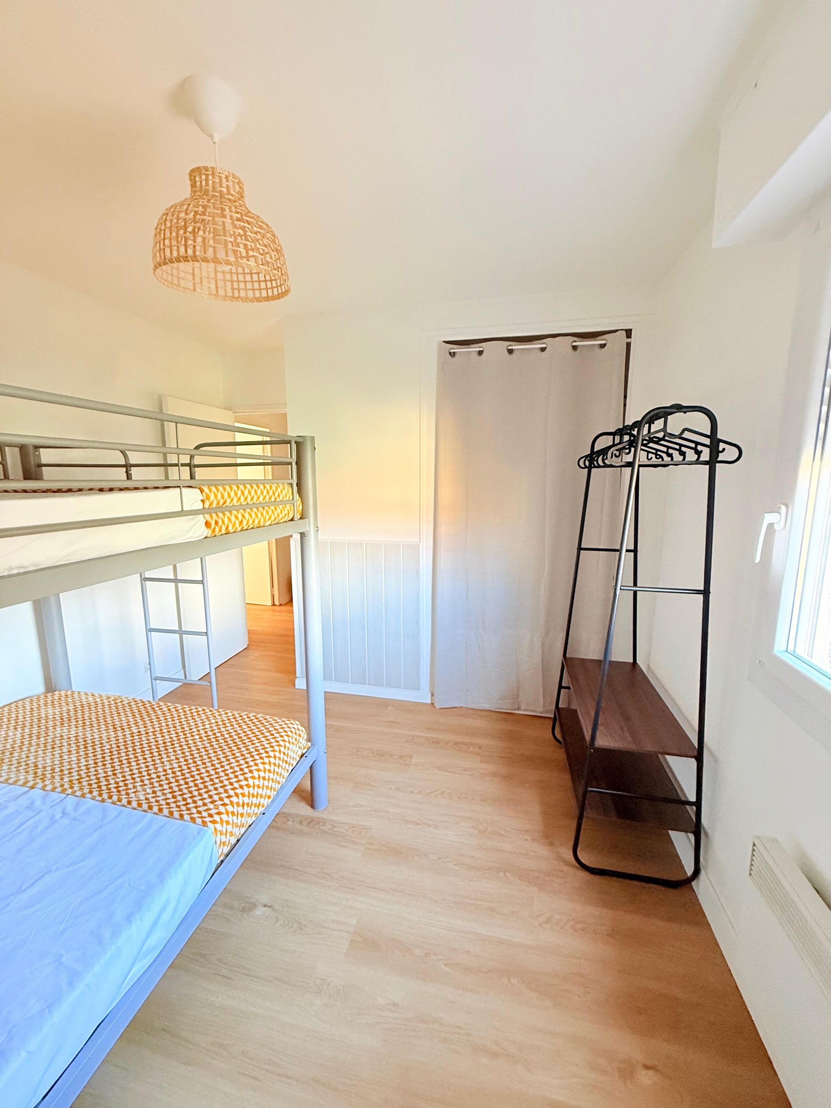 A room with bunk beds, a drying rack, and a hanging light fixture.