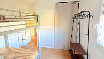 A room with bunk beds, a drying rack, and a hanging light fixture.