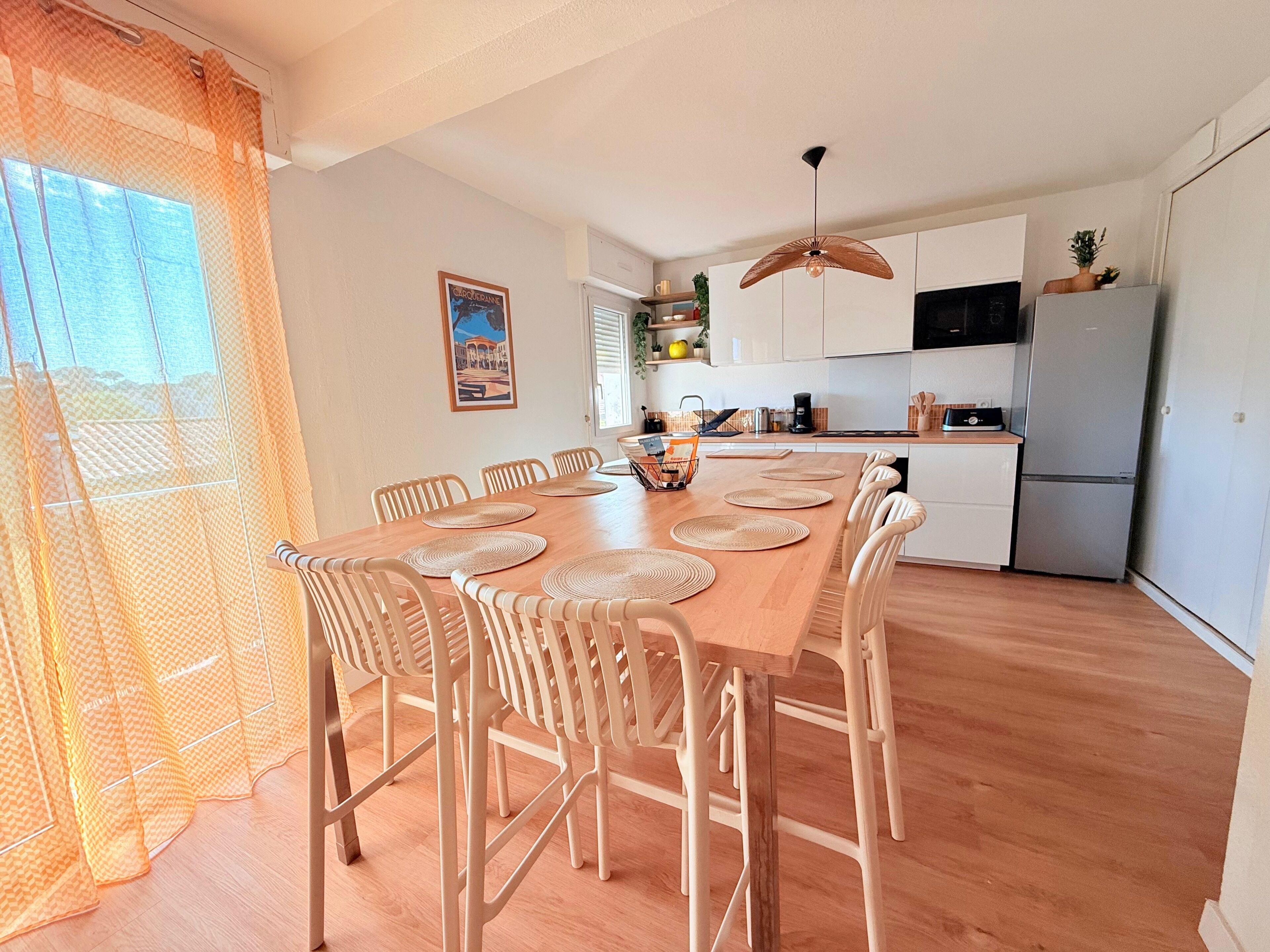 A dining area with a wooden table, chairs, and a kitchen in the background.