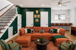 A living room with a sectional sofa, a coffee table, and a staircase.