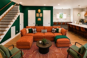 A modern living room with a sectional sofa, a coffee table, and a staircase.