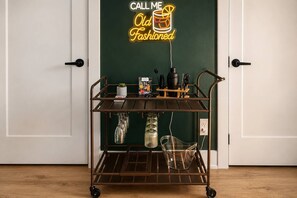 A metal cart with shelves, a neon sign, and a door in the background.