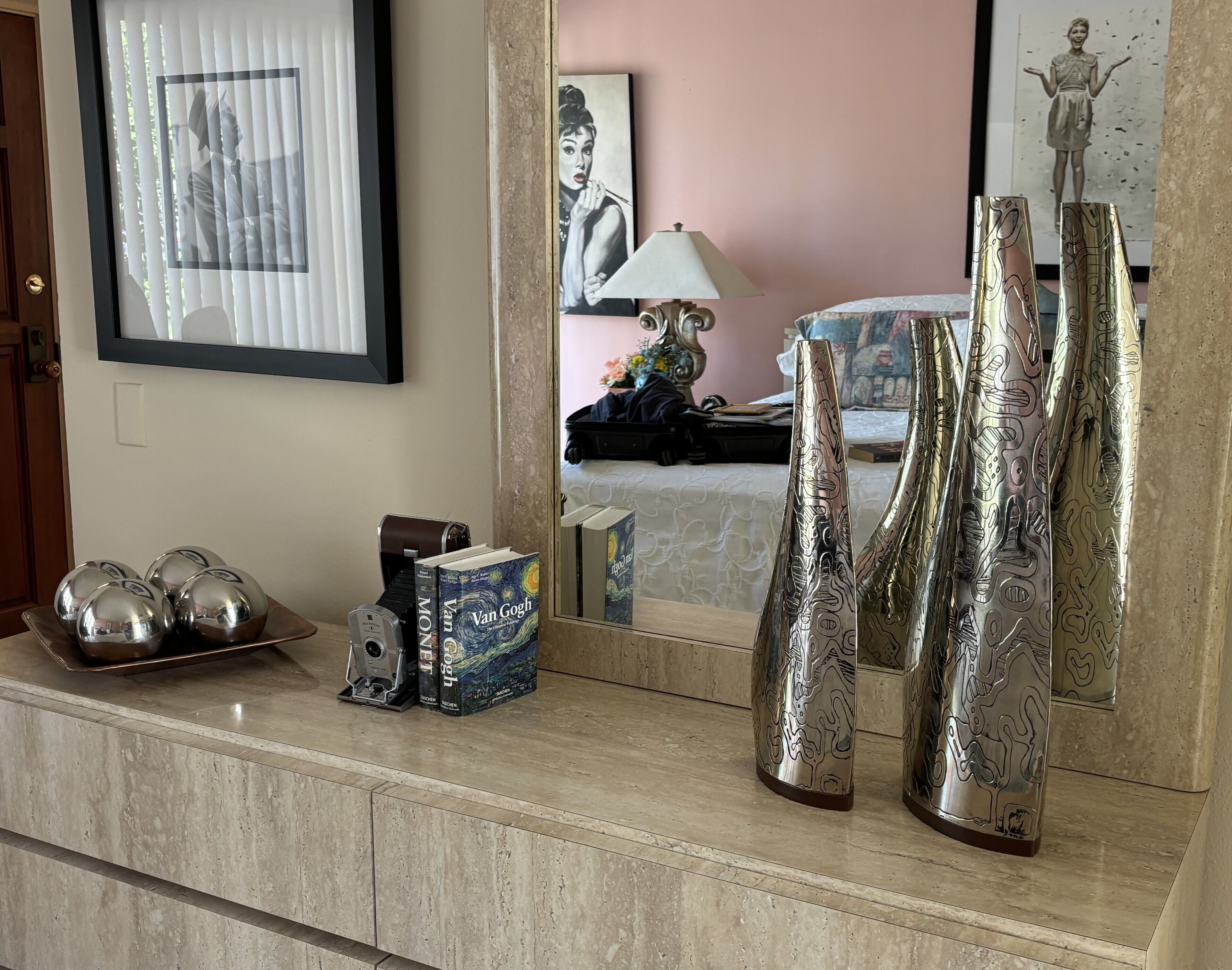 A room with a marble counter, a framed picture, a lamp, and decorative vases.