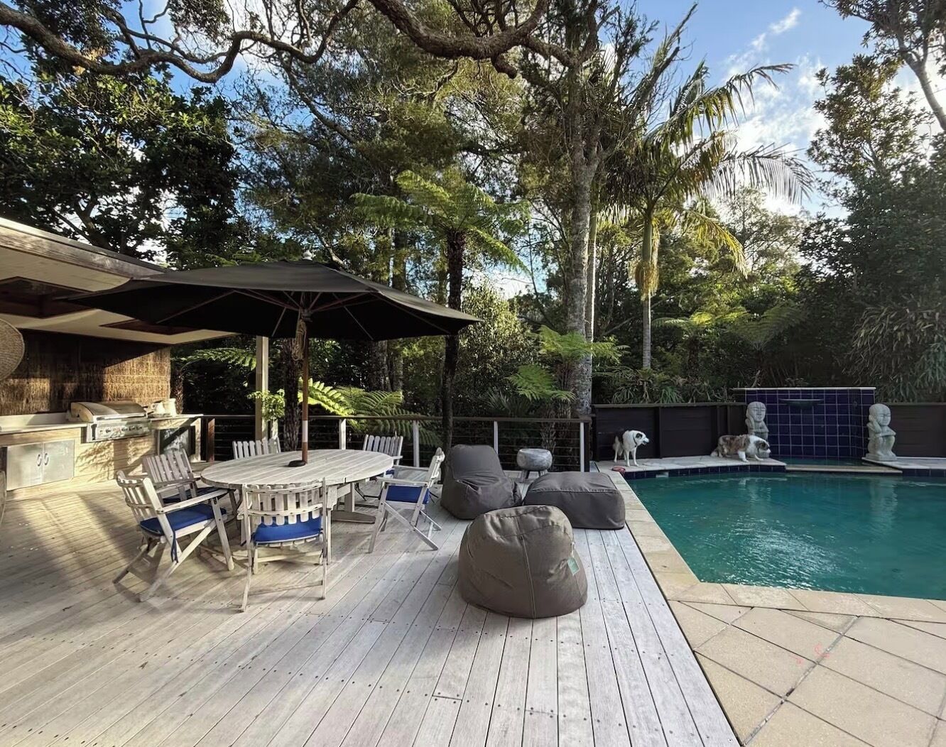 Una terrazza esterna con barbecue, tavolo da pranzo, sedie e zona piscina.