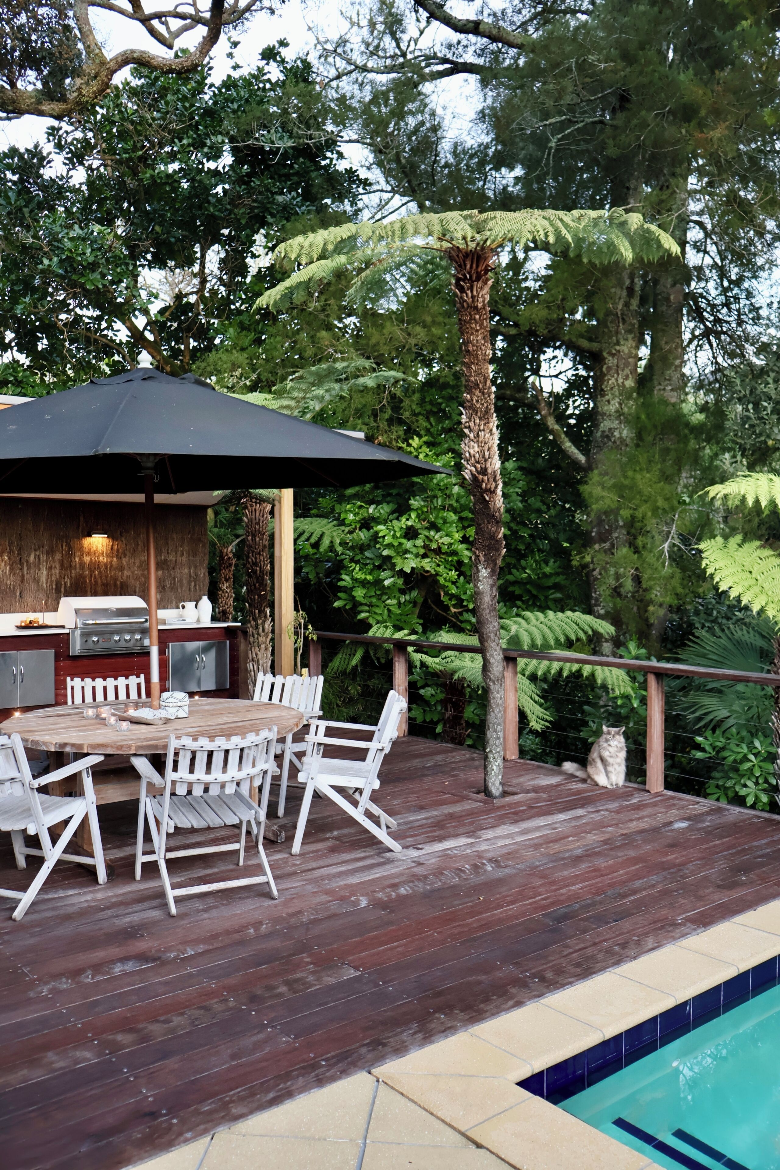Un'area pranzo all'aperto con tavolo e sedie, un barbecue e un ombrellone.