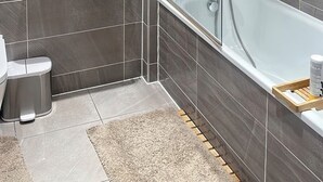Ein modernes Badezimmer mit einer begehbaren Glasdusche, einer freistehenden Badewanne und einem Waschtisch.