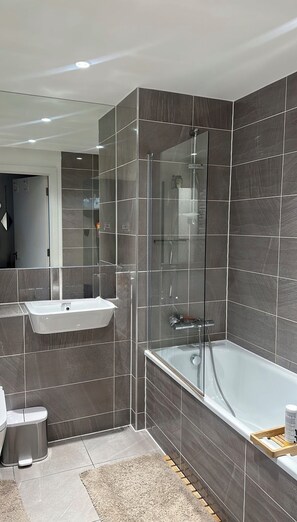 Une salle de bain moderne dotée d’une douche à parois de verre, d’une baignoire sur pieds et d’un meuble-lavabo.