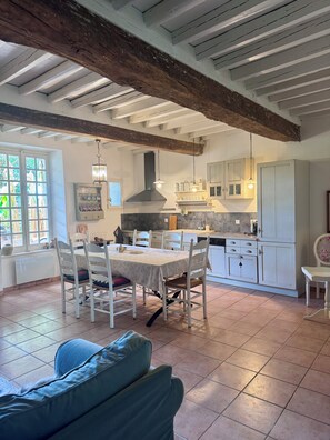 Een eetgedeelte met een tafel voor vier personen, een bank en een keuken op de achtergrond.
