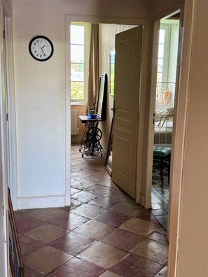 A hallway with a clock on the wall, a sewing machine, and a door leading to another room. - Charming cottage on the Lot River, "Les Tabacs," with a fenced-in private garden. (Clairac)