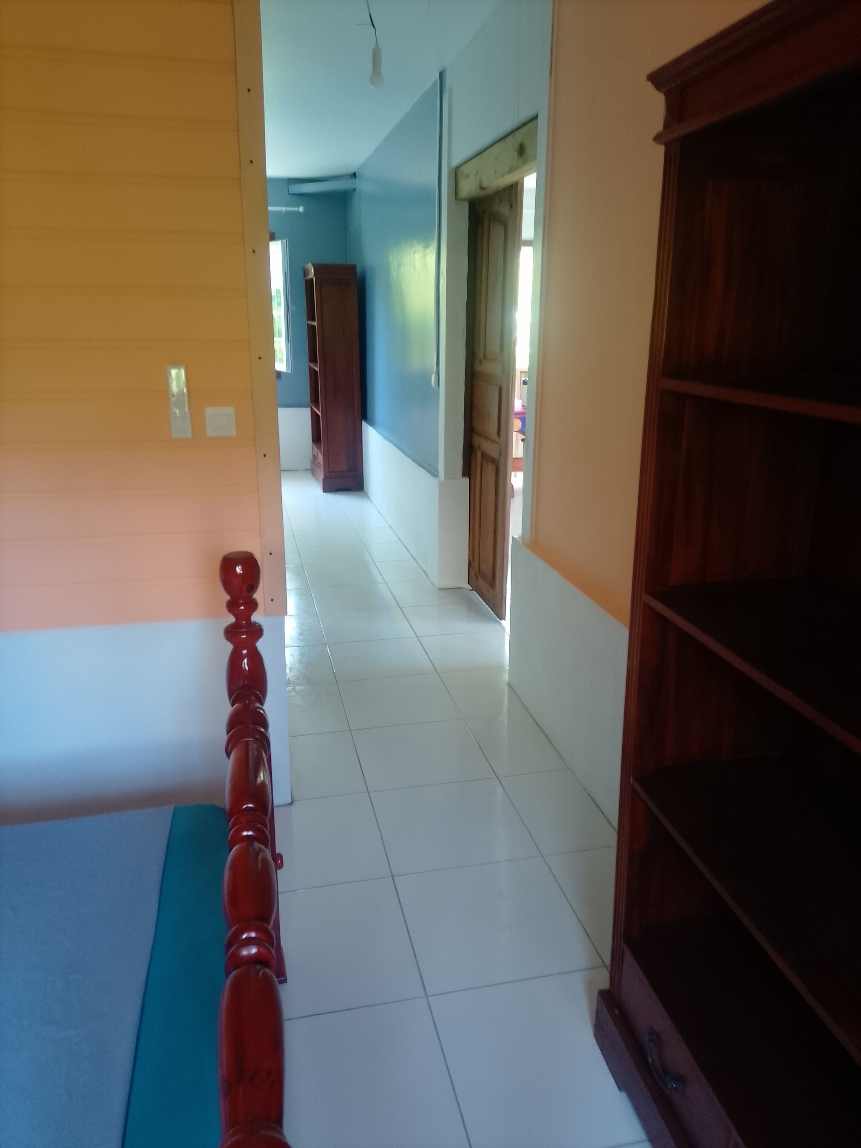 A hallway with a wooden door, a white wall, and a blue wall.