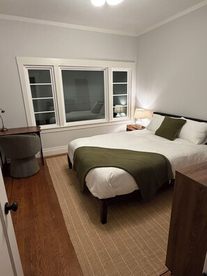 A bedroom with a bed, a desk, a chair, a window, and a nightstand. - Furnished 4BR Home by Golden Gate Park — Walk to UCSF Parnassus (San Francisco)
