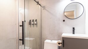 Un bagno moderno con doccia vetrata, un water e un lavandino con specchio.