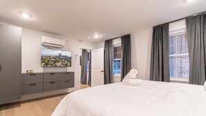 Una camera da letto moderna con un letto grande, una televisione a schermo piatto appesa al muro e vista sulla città dalla finestra.