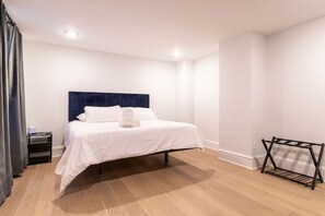 A bedroom with a bed, a nightstand, a towel, and a drying rack. - Spruce Villa - 3rd Floor King 1BR (Philadelphia)