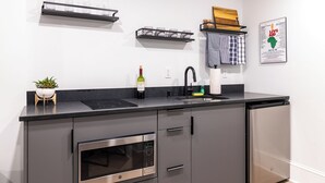 Una cucina moderna con un piano di lavoro nero, elettrodomestici in acciaio inossidabile e una bottiglia di vino.