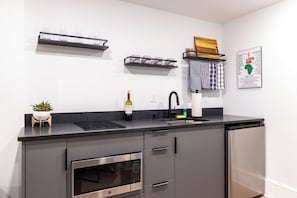 Una cocina moderna con encimera negra, electrodomésticos de acero inoxidable y una botella de vino.