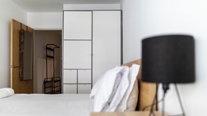 Et soveværelse med seng, natbord, lampe, garderobeskab og et spejl.